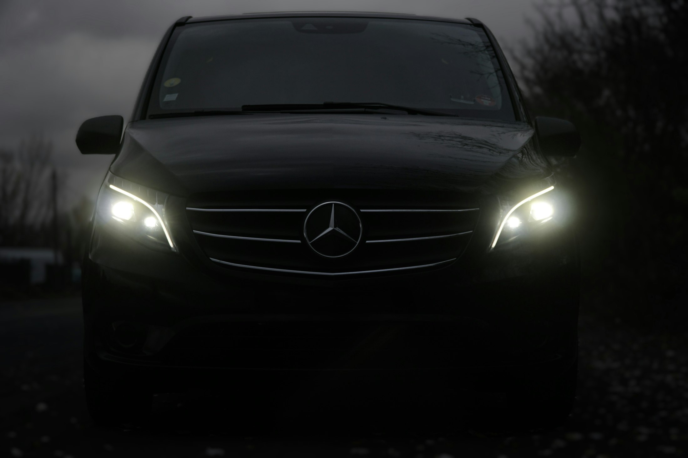 Black Mercedes van with its headlights on at night